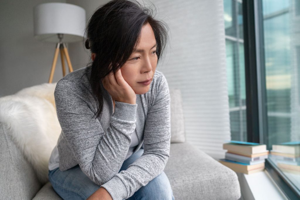 Depressed Asian woman staring out a window
