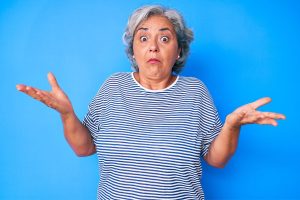 gray haired woman with arms up questioning why she feels angry