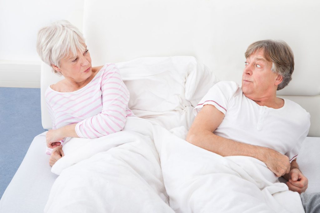 wife angrily looking at husband in bed