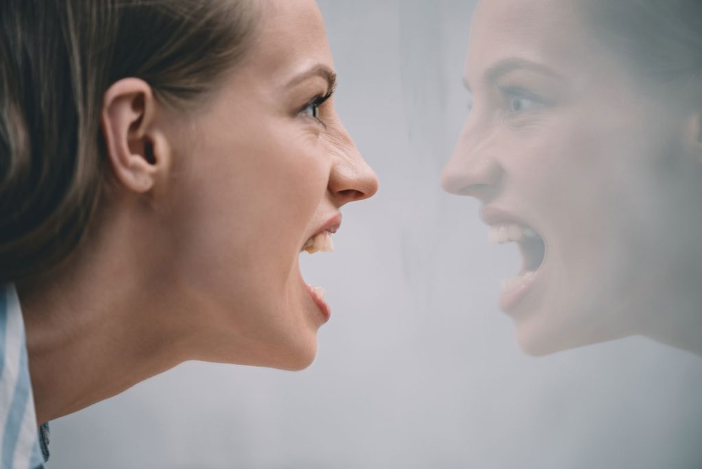 woman full of rage looking at self in mirror