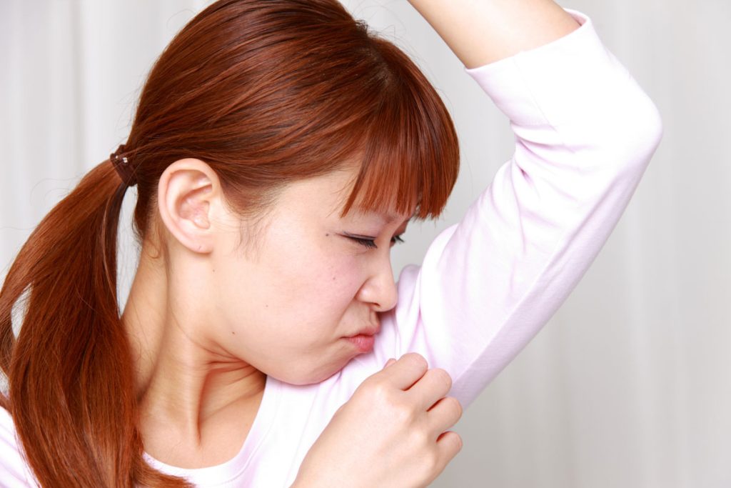 woman smelling her body odor from armpits