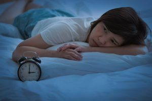 woman staring at alarm clock in the middle of the night