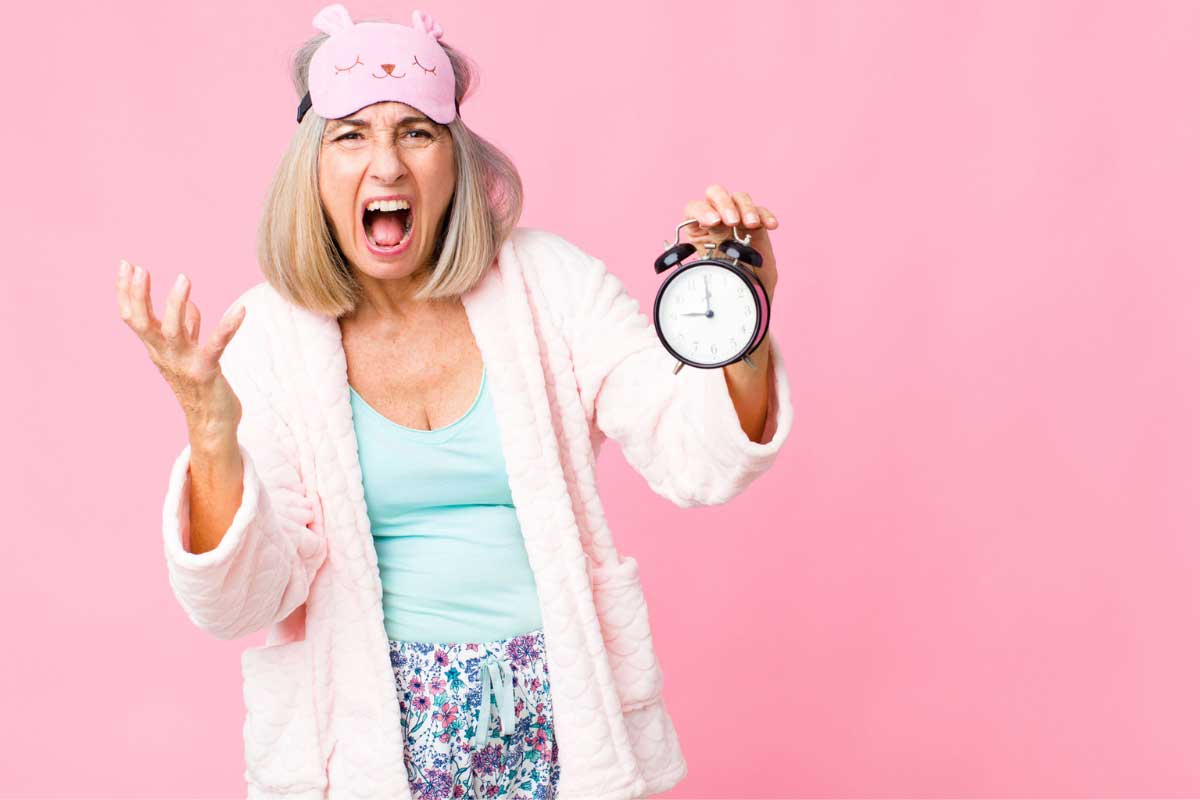 woman upset she can't sleep holding alarm clock