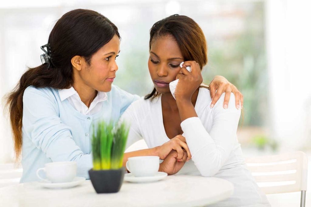 woman consoling a friend who is sad over medical gaslighting