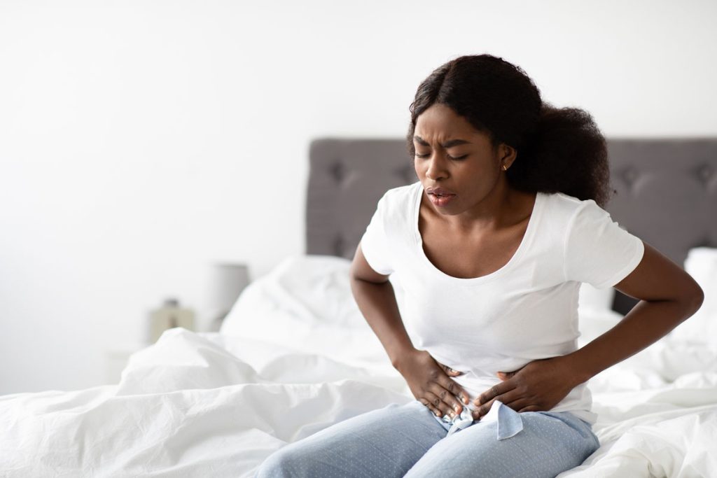 black woman suffering from endometriosis touching pain points