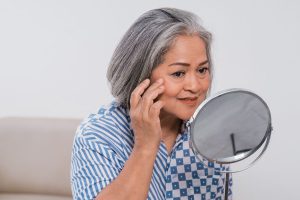 woman looking at her skin and nails in mirror
