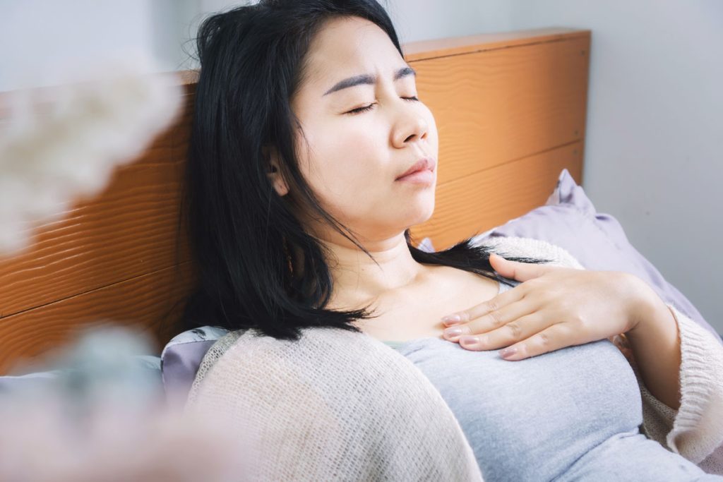 woman holding chest from heartburn