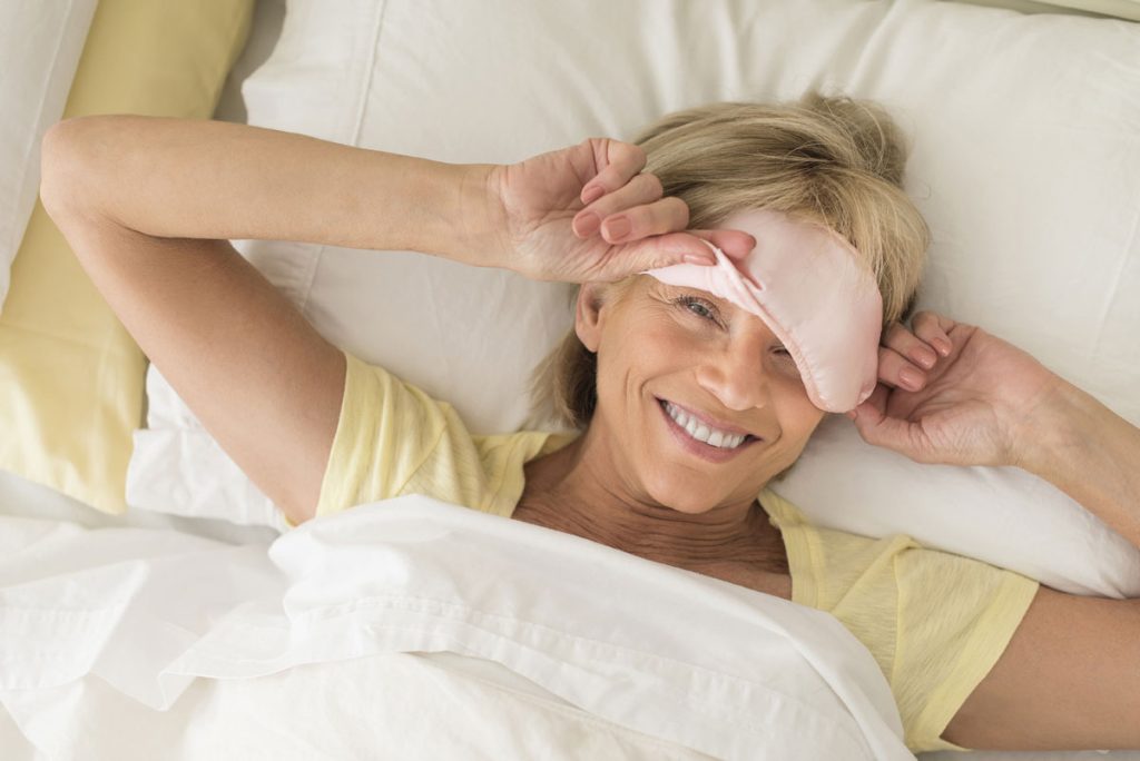 woman peeking through sleeping mask ready for sleep
