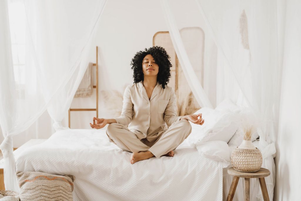 woman sitting in bed taking deep breaths