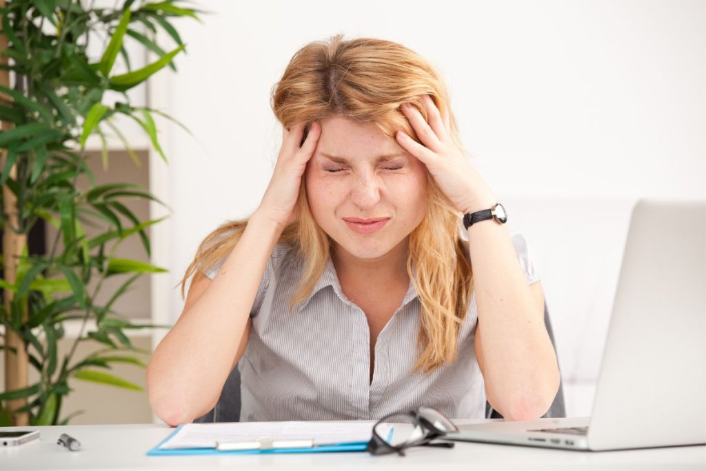 woman with hands on head at work trying to cope