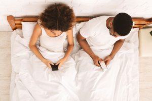 couple texting in bed uninterested in sex