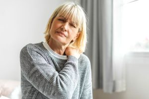woman grabbing shoulder due to muscle aches and pains