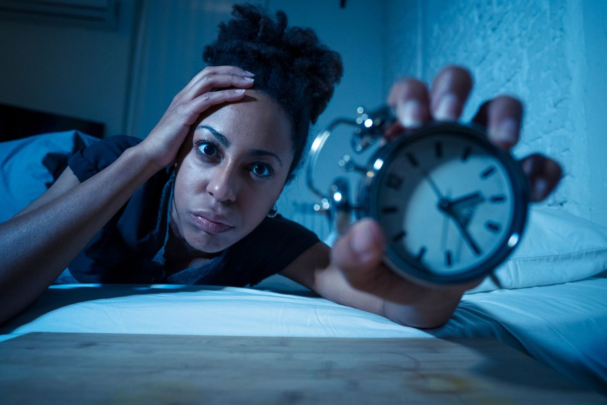 woman holding alarm clock wide awake at night