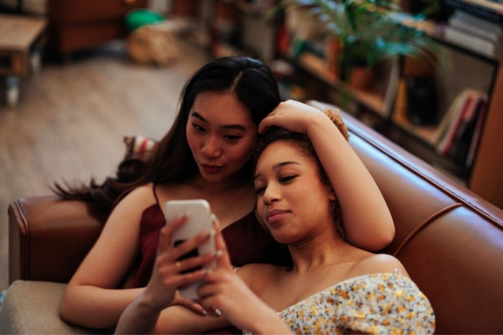 Bisexual lesbian couple on couch looking at phone