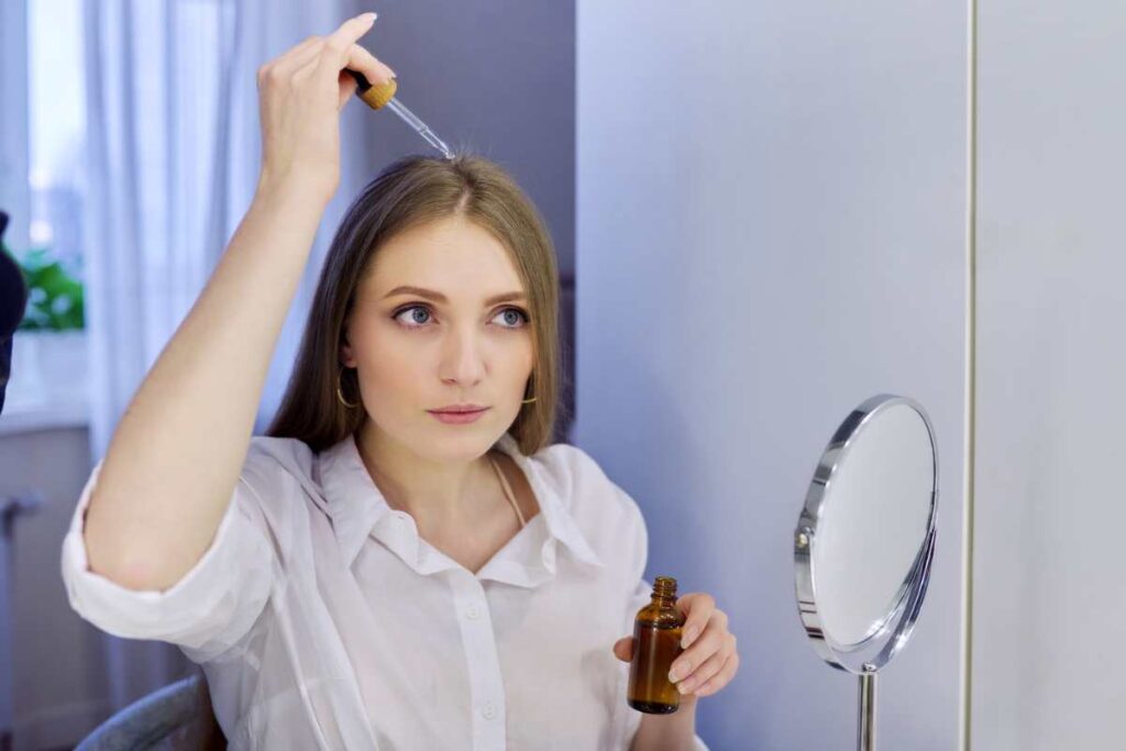 woman putting hair drops on scalp to help it grow