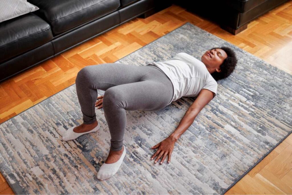 Woman doing bridge yoga pose in living room