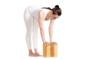 Woman using blocks for standing forward bend pose to relieve stress and anxiety