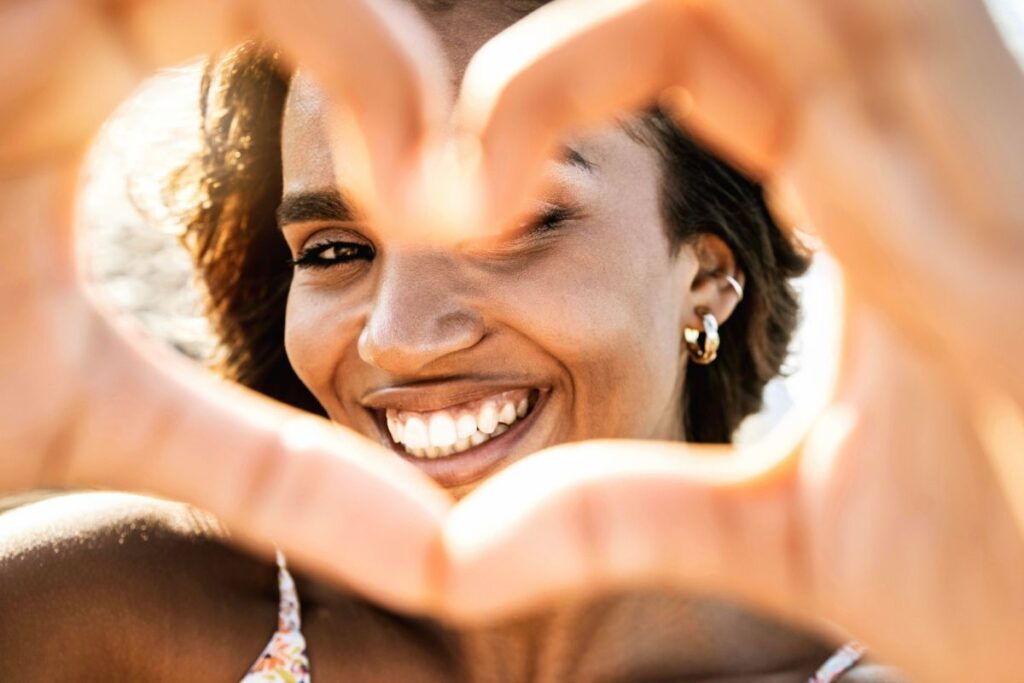 Woman with hands in shape of heart focused on self-care